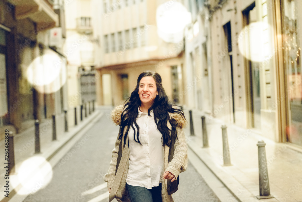 Middle-aged woman smiling and laughing happily walking through the city.