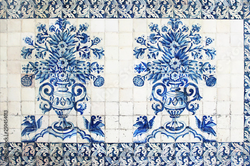 Blue traditional Portuguese ceramic tiles azulejos. Facade, wall decoration of old Coimbra university building, Portugal. Decorative background with ornaments, vase of flowers and parrot birds.