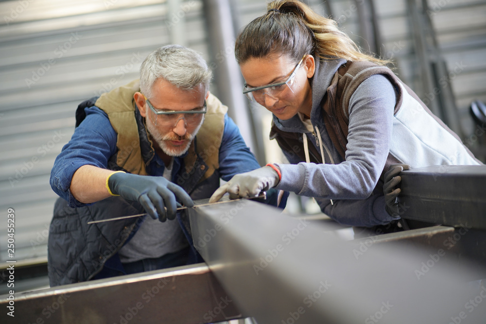 Metalworker with apprentice in workshop Metalworker with apprentice in workshop