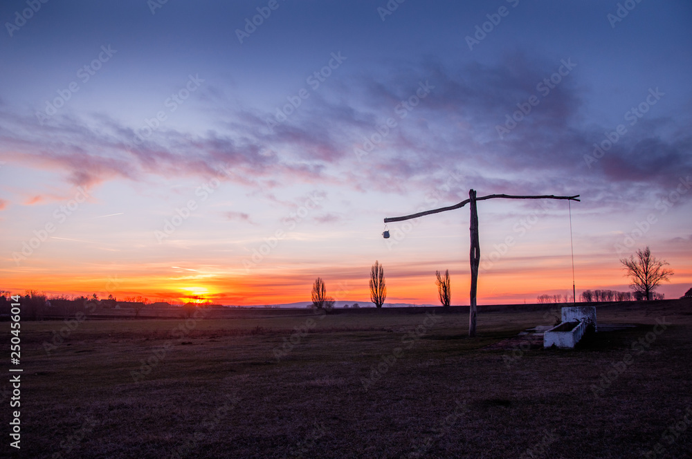 Traditional water well (well sweep or shadoof) in Serbia with a beautifull sunset