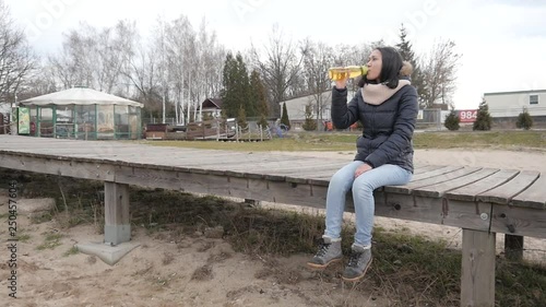 Young Latin Venezu Woman drinks Water from plastic Bottle on a Winter Lake Shore photo