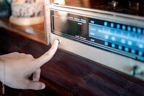 Murais de parede Male hand turning on retro radio by pressing power button