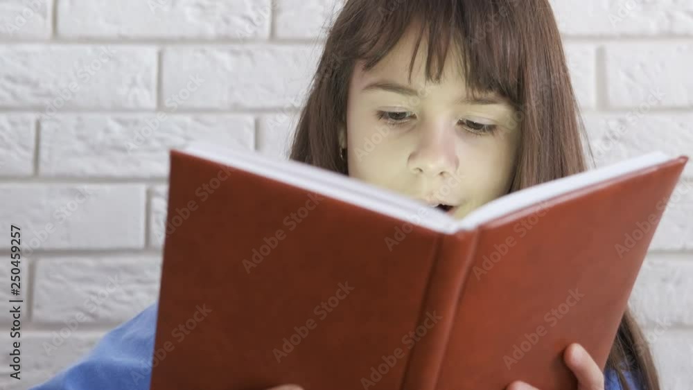 Surprised child with a book. The little girl opens the book and is surprised. Surprised child with a book. The little girl opens the book and is surprised.