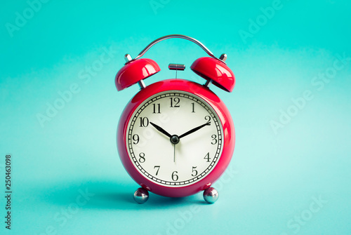 Close up red alarm clock on blue pastel background