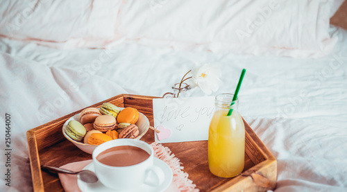 Breakfast in bed with i love you text on a note. Cup of coffee or cocoa, juice, macaroons, rose flower on wooden tray. Romantic breakfast in bed. Birthday, Valentine's day morning. Copy space.