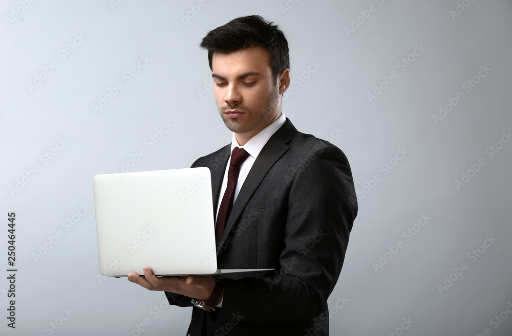 Portrait of handsome young businessman with laptop on light background Portrait of handsome young businessman with laptop on light background