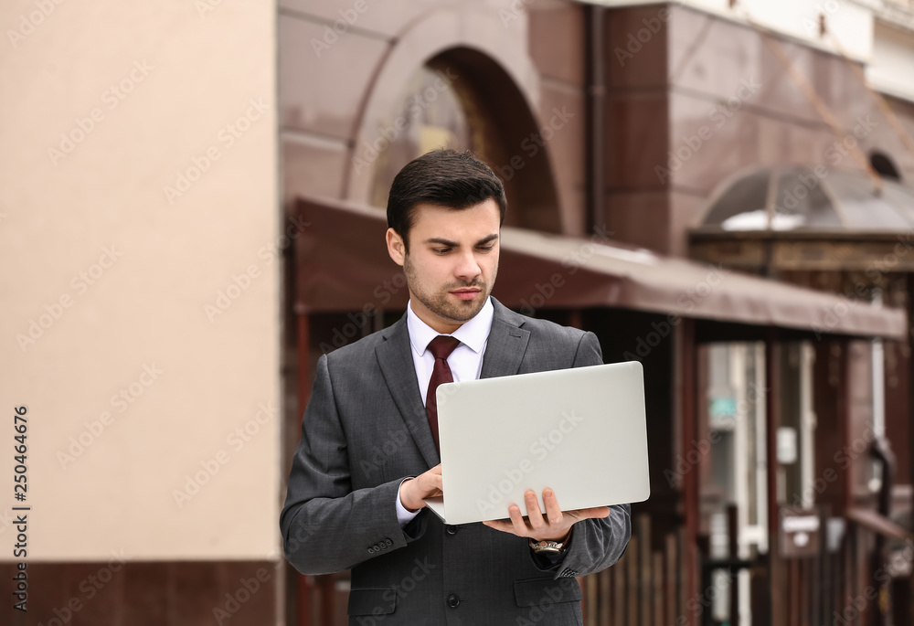 Portrait of handsome young businessman with laptop outdoors Portrait of handsome young businessman with laptop outdoors