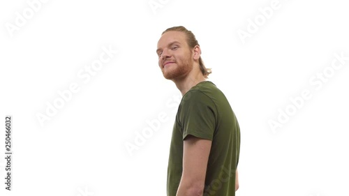 Slowmo back view handsome bearded ginger young guy turning camera inviting joing come with him, smiling friendly, call friend pointing head direction time go together, standing white background photo