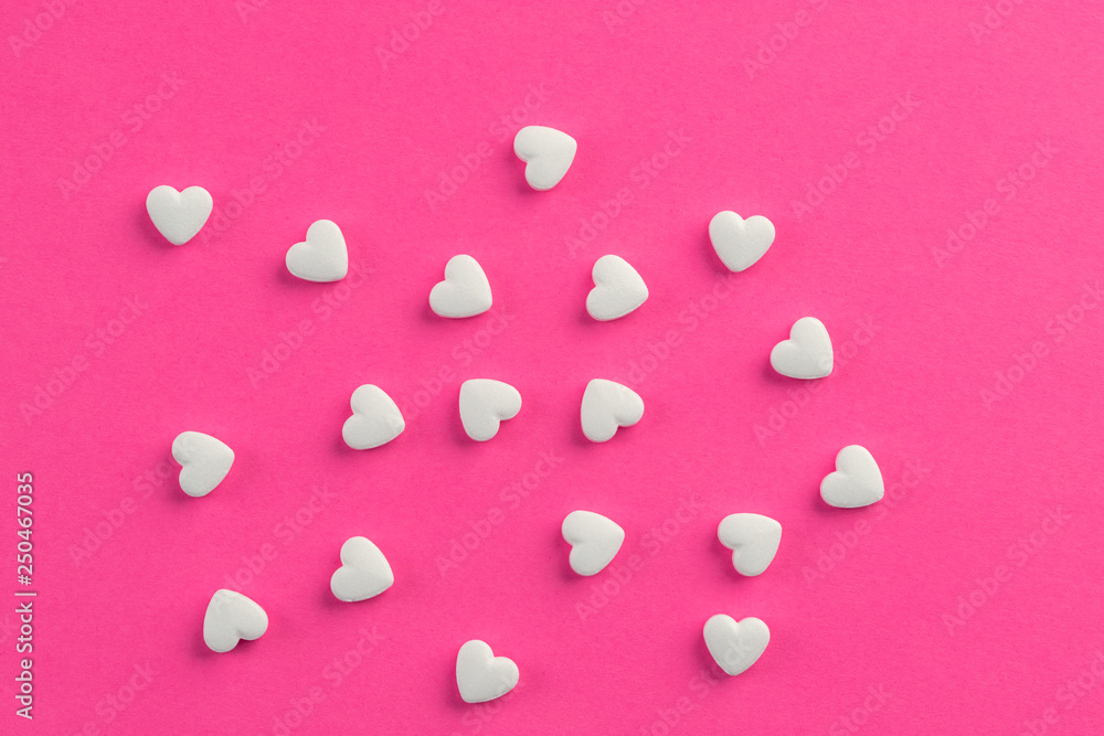 White heart shaped pills on pink background. White heart shaped pills on pink background.