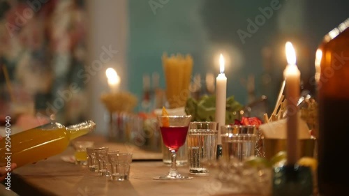 Professional bartender pouring orange drink into a small glasses in the bar with soft interior lighting photo