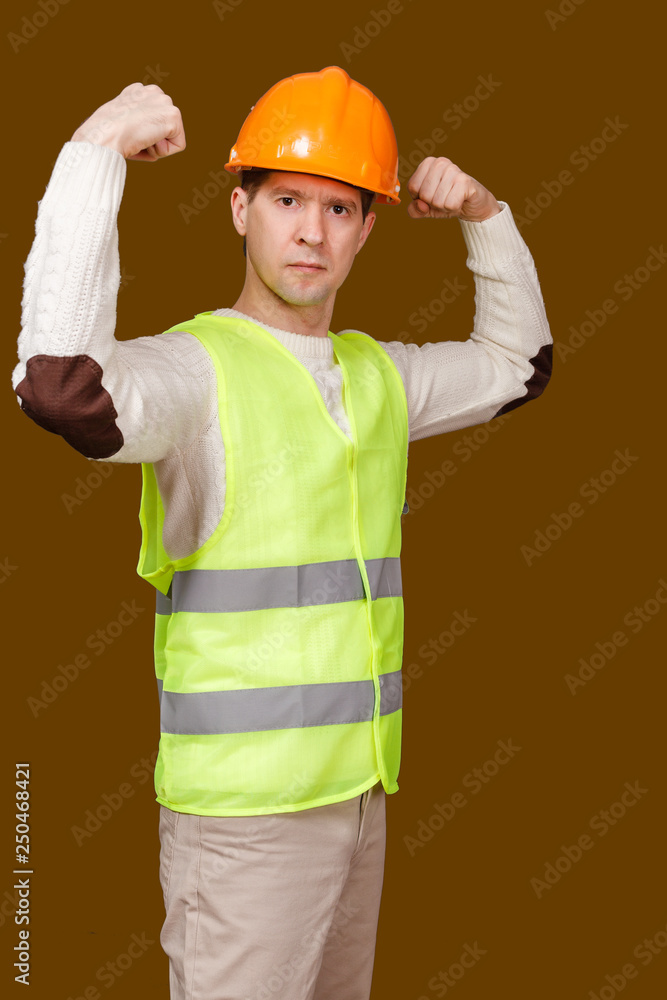 the man in a construction helmet, a vest shows force of a biceps of the hands bent in an elbow the man in a construction helmet, a vest shows force of a biceps of the hands bent in an elbow