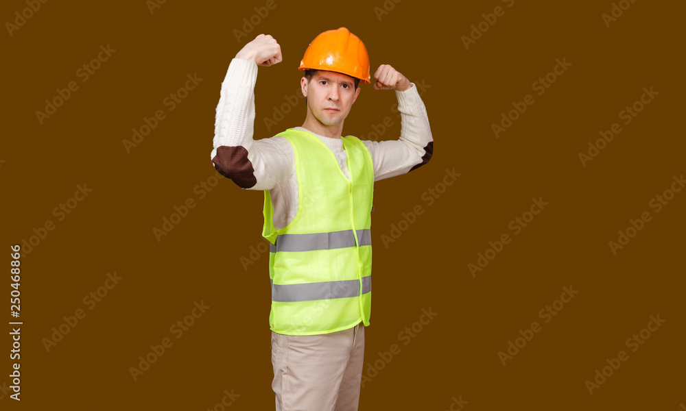 the man in a construction helmet, a vest shows force of a biceps of the hands bent in an elbow the man in a construction helmet, a vest shows force of a biceps of the hands bent in an elbow