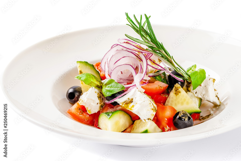 Concept of Greek cuisine. Salad of tomato, cucumber, bell pepper, olives and feta cheese. dressed with olive oil and decorated with fresh basil. White plate on a white background. Concept of Greek cuisine. Salad of tomato, cucumber, bell pepper, olives and feta cheese. dressed with olive oil and decorated with fresh basil. White plate on a white background.