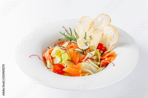 American cuisine concept. Caesar salad with salmon. White plate on a white background. Image for a menu of restaurants or cafes.