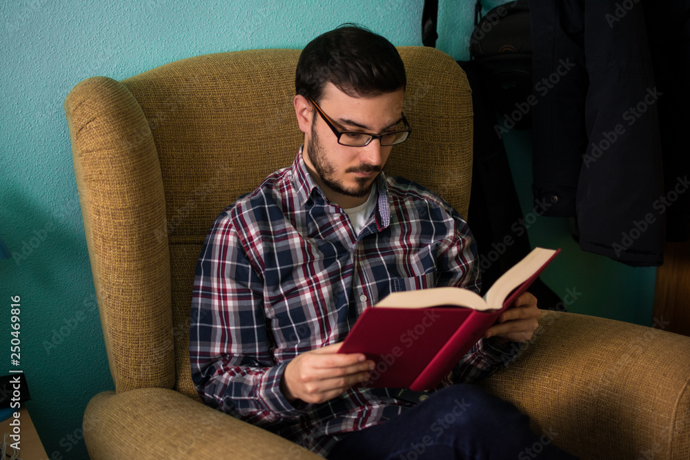 Man reading a book on sofa in his home
