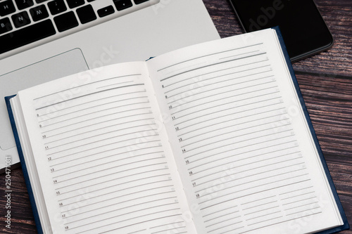 Opened clean business notebook and laptop. Business notebook for record important events and meetings with business partners on the wooden table