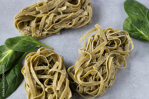 Spinach noodles  and fresh spinach leaves on  gray background. Green tagliatelle. photo