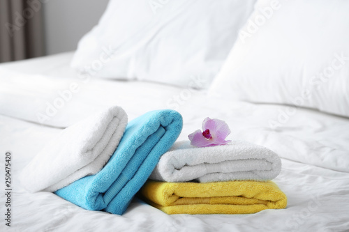 Clean towels and pink orchid on bed © New Africa