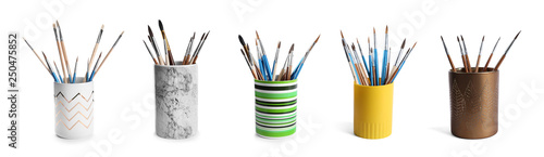 Set of holders with different paint brushes on white background