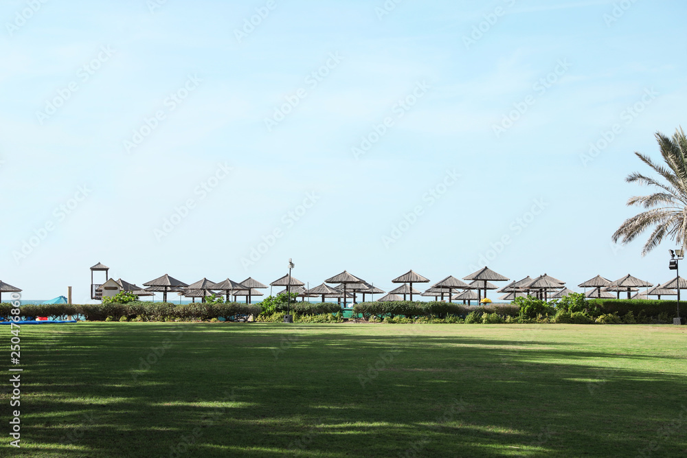 Beautiful landscape with beach umbrellas at tropical resort on sunny day Beautiful landscape with beach umbrellas at tropical resort on sunny day