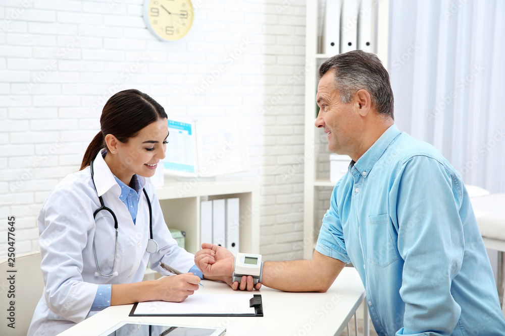 Doctor checking mature man's pulse with medical device in hospital Doctor checking mature man's pulse with medical device in hospital