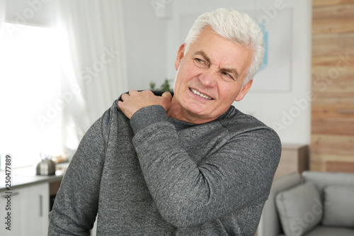 Mature man scratching shoulder at home. Annoying itch