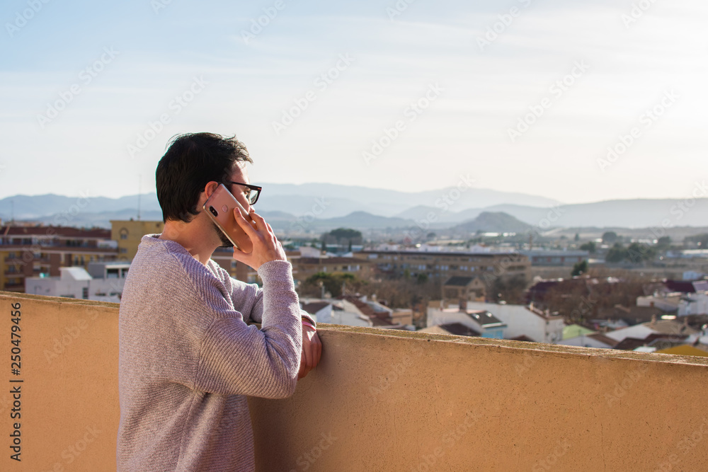 Man using mobile phone on rooftop. Talking in a balcony Man using mobile phone on rooftop. Talking in a balcony