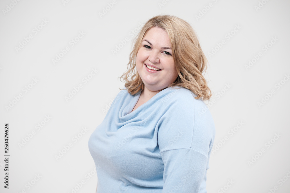 Young obese woman in casual blue clothes on a white background in the studio. Bodypositive. Young obese woman in casual blue clothes on a white background in the studio. Bodypositive.