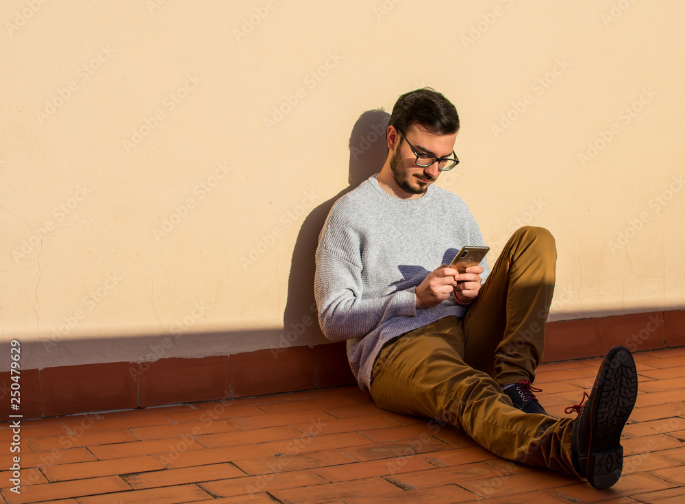 Fototapeta premium Man using mobile phone on rooftop. Talking in a balcony