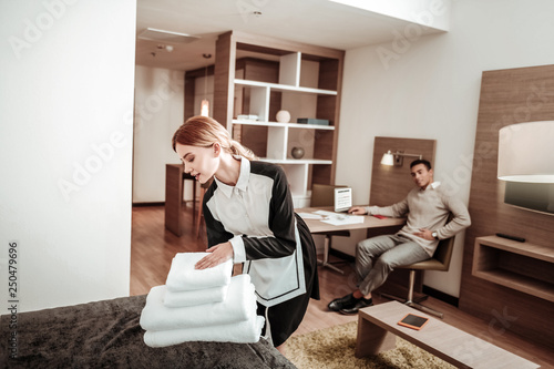 Fotografie Pleasant hard-working housekeeper bringing new white towels