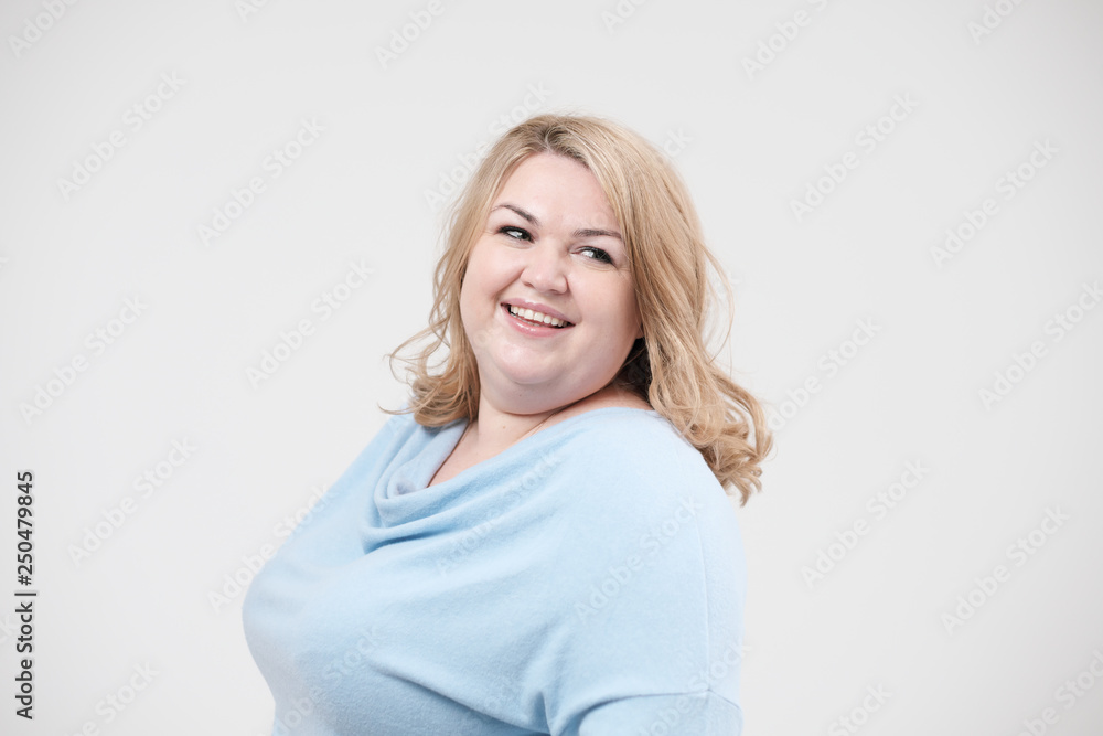 Young obese woman in casual blue clothes on a white background in the studio. Bodypositive. Young obese woman in casual blue clothes on a white background in the studio. Bodypositive.