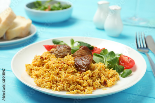 Plate of tasty rice pilaf with meat served on table