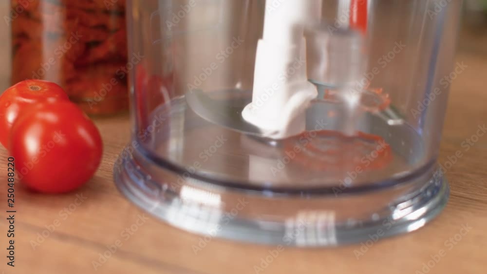 SLOW MOTION, MACRO, DOF: Canned tomato puree is poured into a kitchen blender standing on a wooden countertop. Fresh tomato sauce with small pieces is poured into a blender with sharp steel blades. SLOW MOTION, MACRO, DOF: Canned tomato puree is poured into a kitchen blender standing on a wooden countertop. Fresh tomato sauce with small pieces is poured into a blender with sharp steel blades.