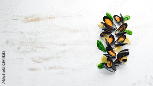 Boiled mussels with spices in a plate. Top view. Free space for your text. On the old background.