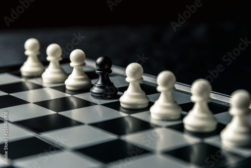 Chess board. Among the white pawns standing in a row is the black pawn of the enemy