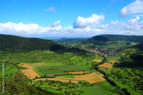 landscape with grain field in valey and blue sky with clouds