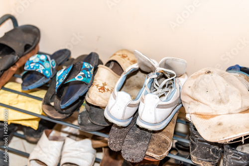 Many pairs of shoes on display on shelf rack with dirty soiled rustic retro cottage farm house home dacha closeup