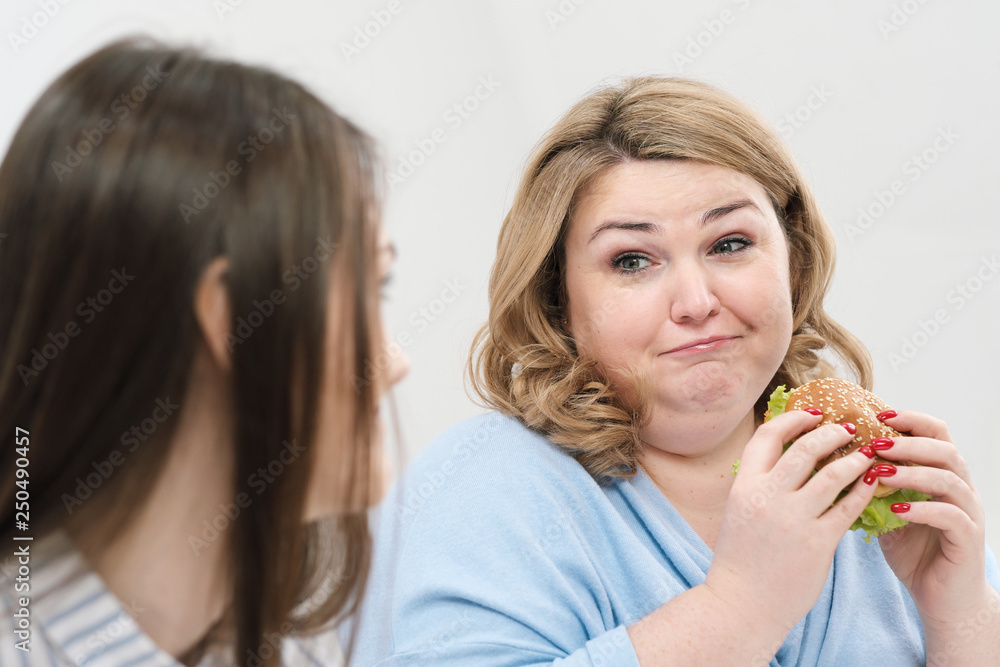 Slender girl eats healthy food, Fat woman eats harmful fast food. On a white background, the theme of diet and proper nutrition. Slender girl eats healthy food, Fat woman eats harmful fast food. On a white background, the theme of diet and proper nutrition.