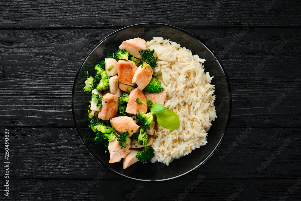 Rice with chicken fillet and vegetables. Top view. On a black background. Free copy space. Rice with chicken fillet and vegetables. Top view. On a black background. Free copy space.
