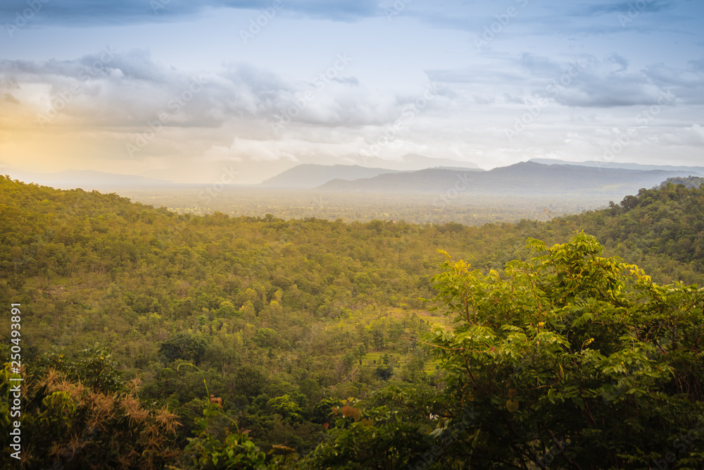 Peaceful landscape of green forest and sunrise or sunset over mountains in Pakse, Champasak, Laos.  Shot zooms from Wat Sirindhorn Wararam Phu Prao, Ubon Ratchathani, Thailand, nearby Chong Mek border