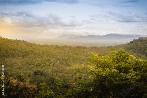 Peaceful landscape of green forest and sunrise or sunset over mountains in Pakse, Champasak, Laos. Shot zooms from Wat Sirindhorn Wararam Phu Prao, Ubon Ratchathani, Thailand, nearby Chong Mek border