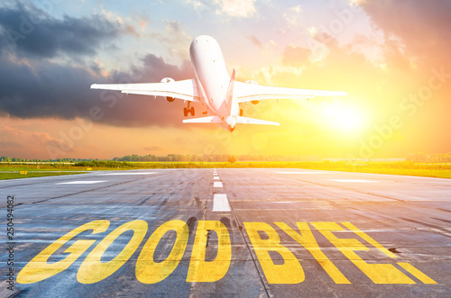 Good luck written on runway airport, and the airplane take off into the sunset. Concept of departure return home