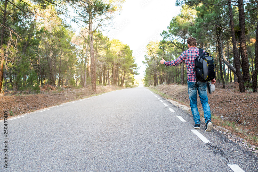Man hitchhiking with thumbs up in a countryside road Man hitchhiking with thumbs up in a countryside road