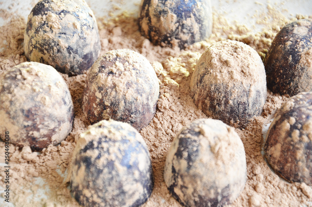Chocolate candy truffle with chocolate pieces and flying cocoa powder on a dark background Chocolate candy truffle with chocolate pieces and flying cocoa powder on a dark background