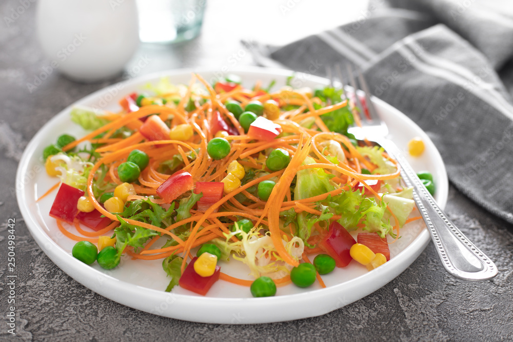 Fresh vegetable salad with raw carrot, green peas, corn, sweet pepper and lettuce. Healthy vegan, vegetarian lunch menu. Top view Fresh vegetable salad with raw carrot, green peas, corn, sweet pepper and lettuce. Healthy vegan, vegetarian lunch menu. Top view