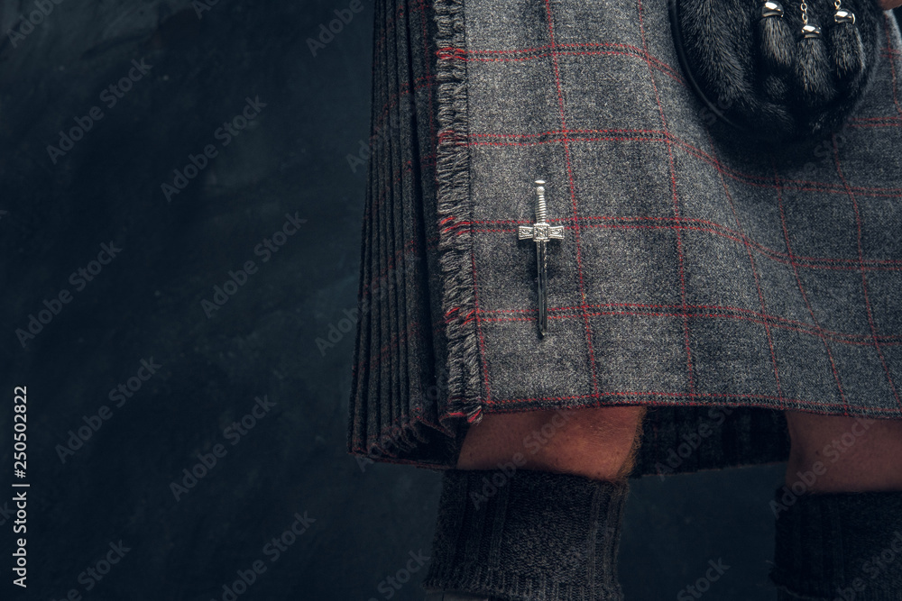Φωτογραφία Close-up photo of a traditional Scottish costume against a dark textured wall