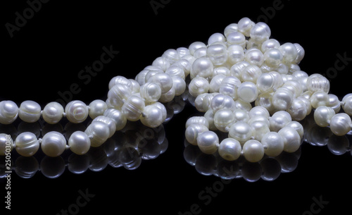 Natural white pearl beads on a black background with reflection