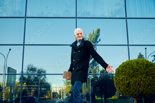 happy successful old man in black coat walking for city