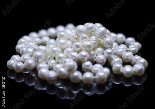 Natural white pearl beads on a black background with reflection