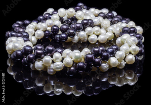 Two mixed strands of natural black pearl beads on a black background with reflection